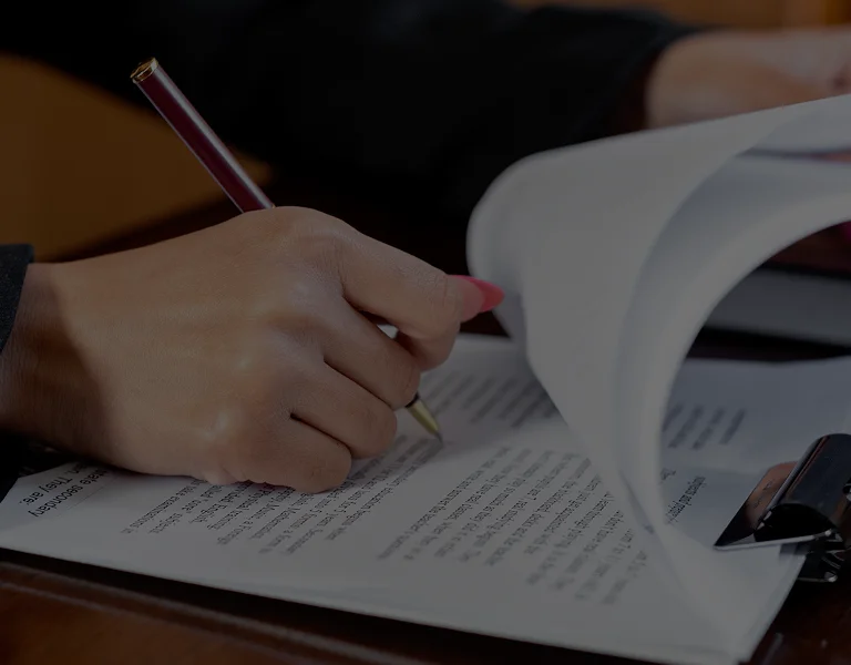 Close-up of a person signing a document with a pen on a clipboard.