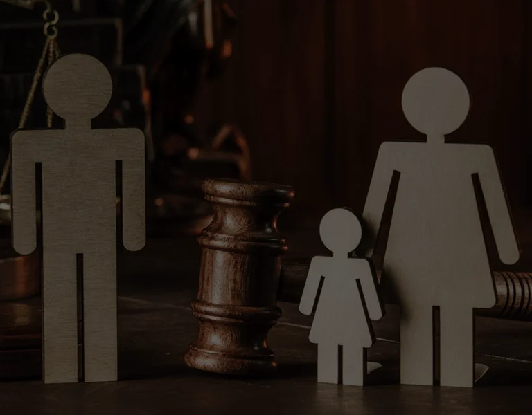 Wooden figures of a man, woman, and child with a judge's gavel in background.