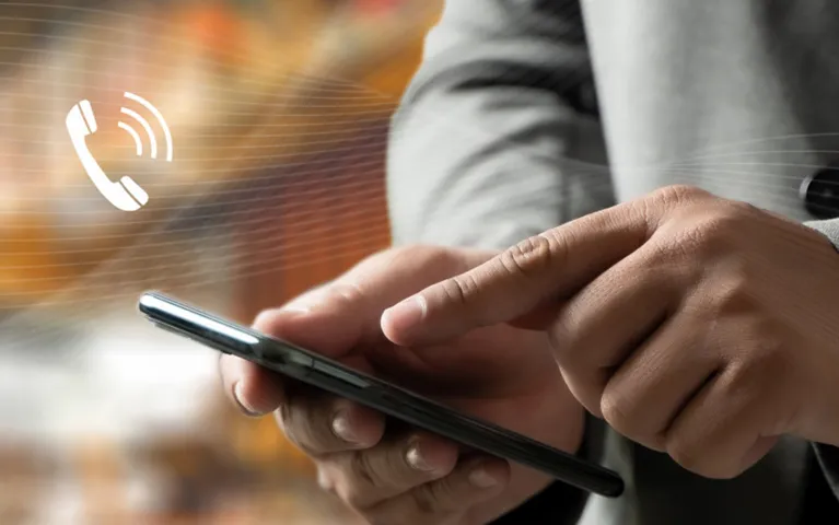 Person in gray suit using smartphone with white phone call icon overlay.