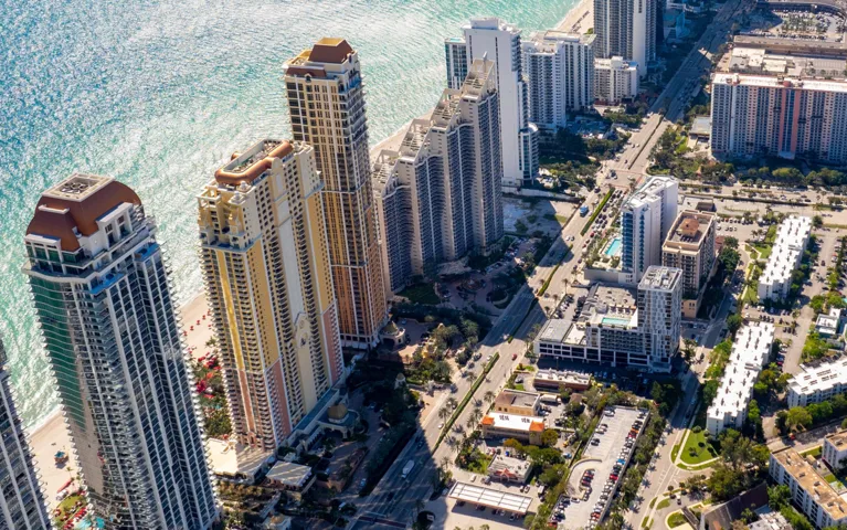 Aerial view of coastal city with high-rise buildings, streets, and ocean shore.
