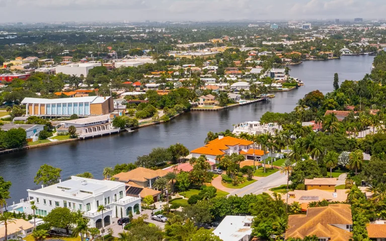 Aerial view of a residential neighborhood with a river, houses, and abundant greenery.